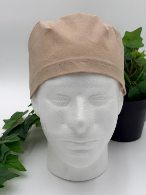 Beige scrub cap on a mannequin head with a white background and green plants.