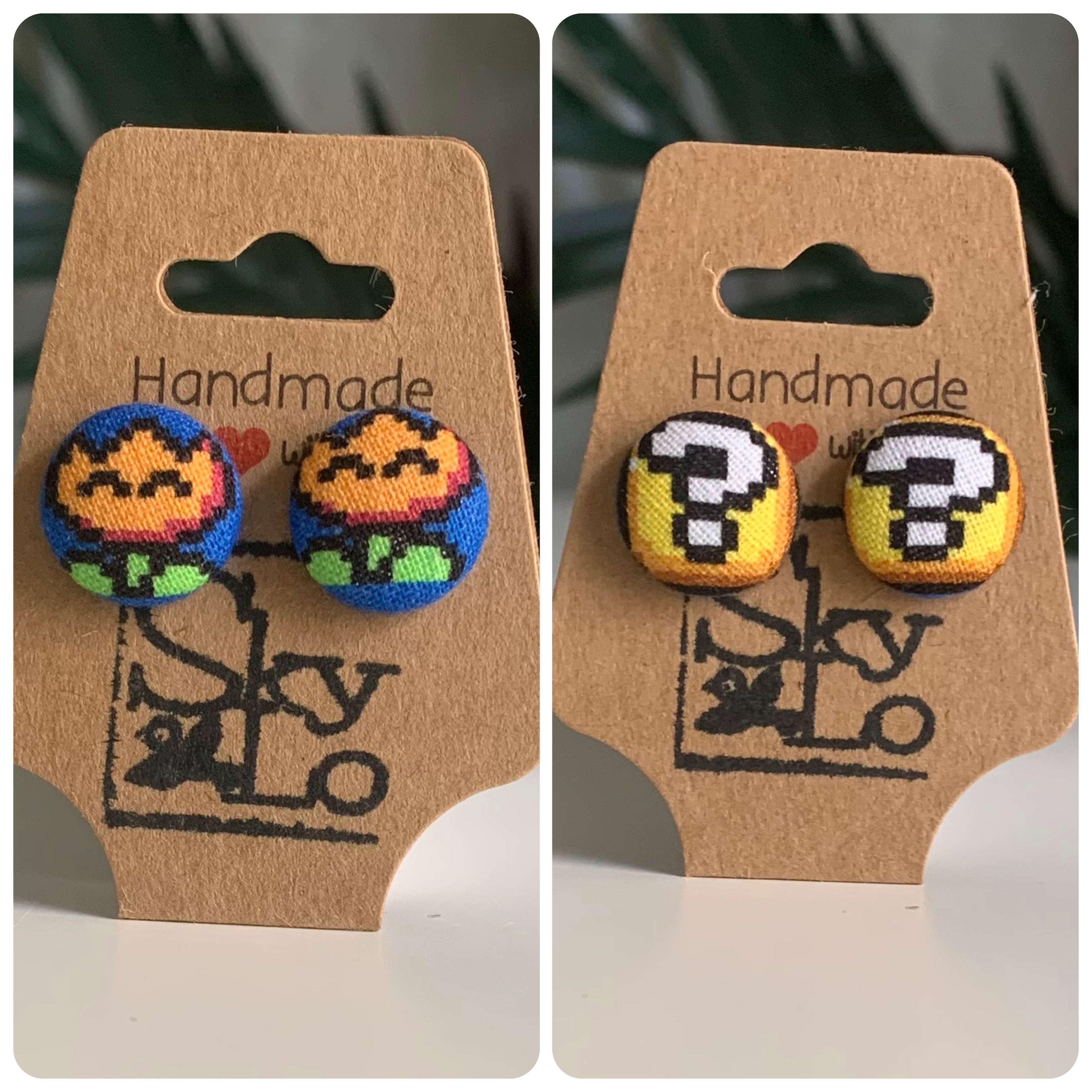 Pair of Mario bros fire flower and question block earrings on a 'Handmade' branded card with a logo.