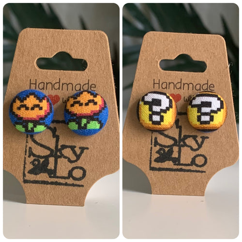 Pair of Mario bros fire flower and question block earrings on a 'Handmade' branded card with a logo.