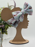 Headband with a decorative christmas themed big bow on a mannequin head silhouette against a white background