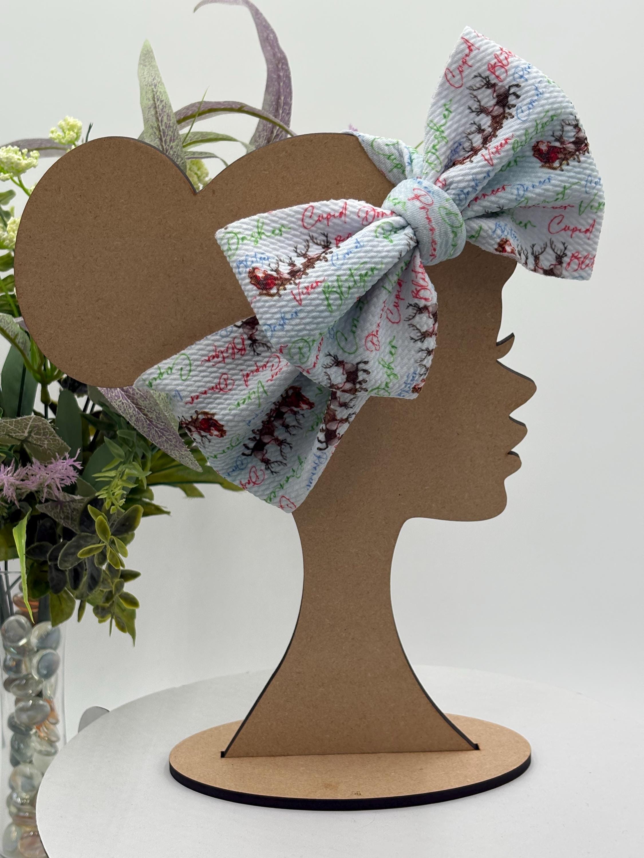 Headband with a decorative christmas themed big bow on a mannequin head silhouette against a white background