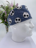 Mannequin head wearing a jack skellington scrub cap with a decorative plant in the background.