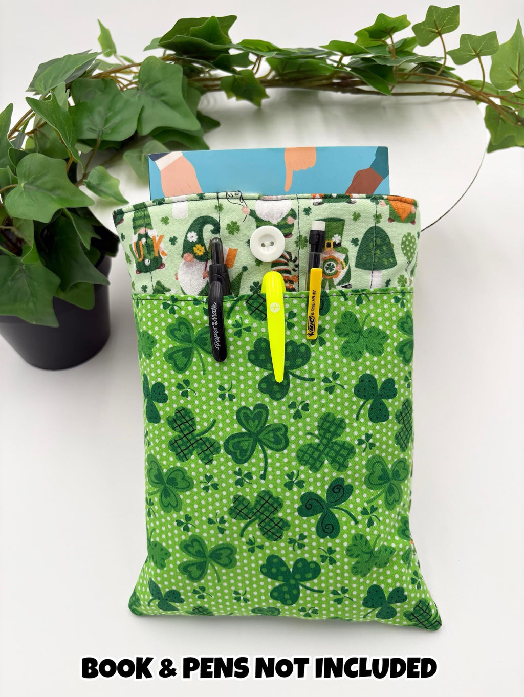Green saint Patrick’s day gnomes and shamrocks patterned book sleeve with pens and book on a white surface and text “book and pens not included”