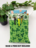 Green saint Patrick’s day gnomes and shamrocks patterned book sleeve with pens and book on a white surface and text “book and pens not included”
