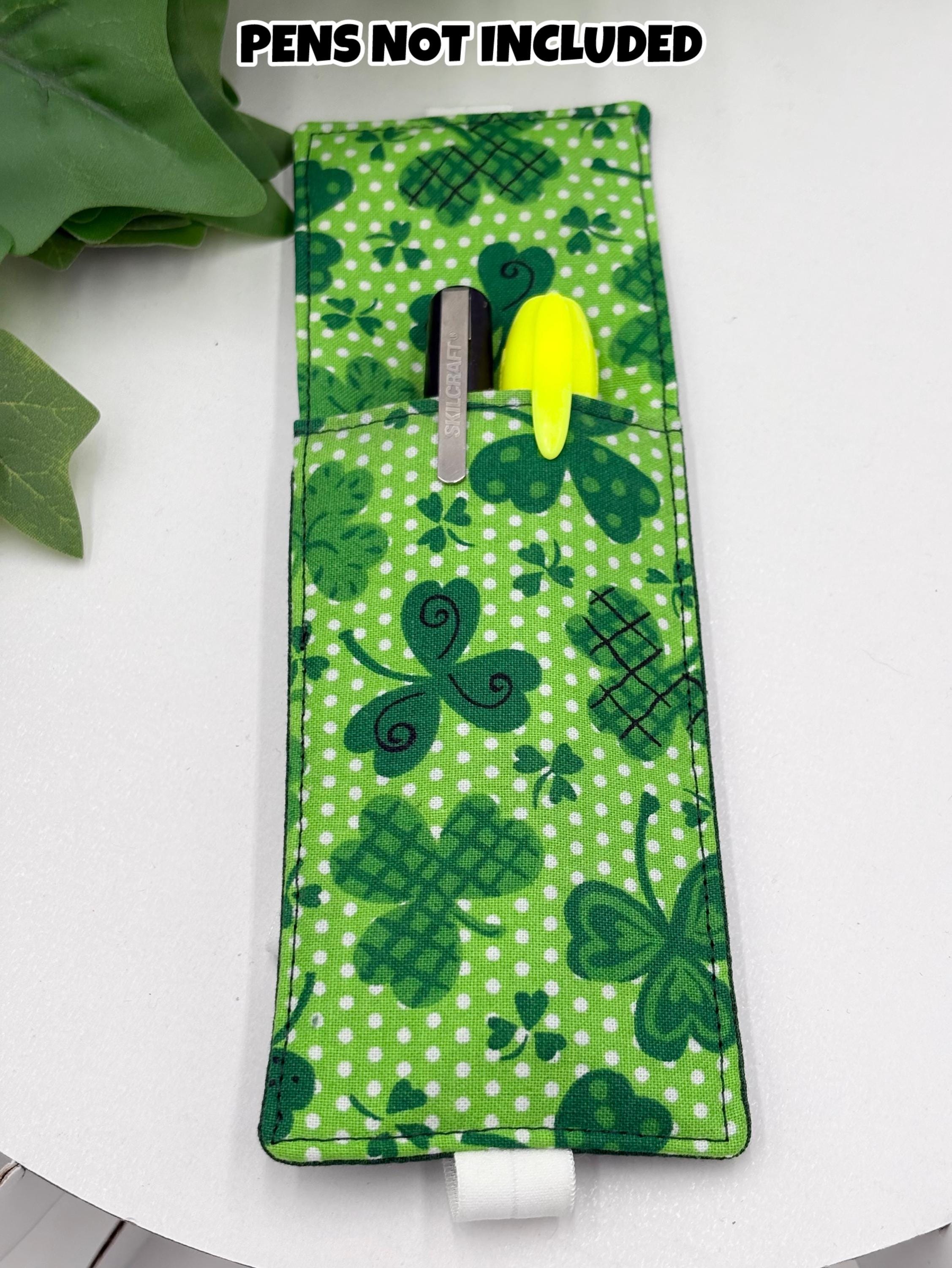 Green shamrock patterned pen holder on a white surface with text 'PENS NOT INCLUDED'.