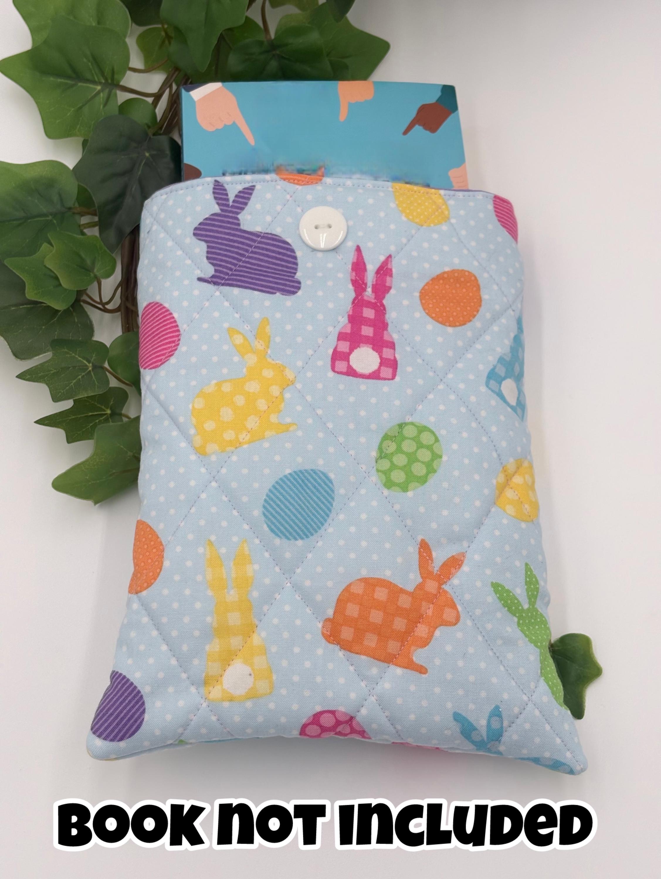 Colorful quilted pouch with rabbit and egg pattern on a light blue background, surrounded by green leaves. Text says book not included