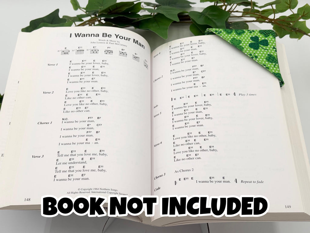 Open book with text,  with green shamrock corner bookmark attached and  green leaves in the background