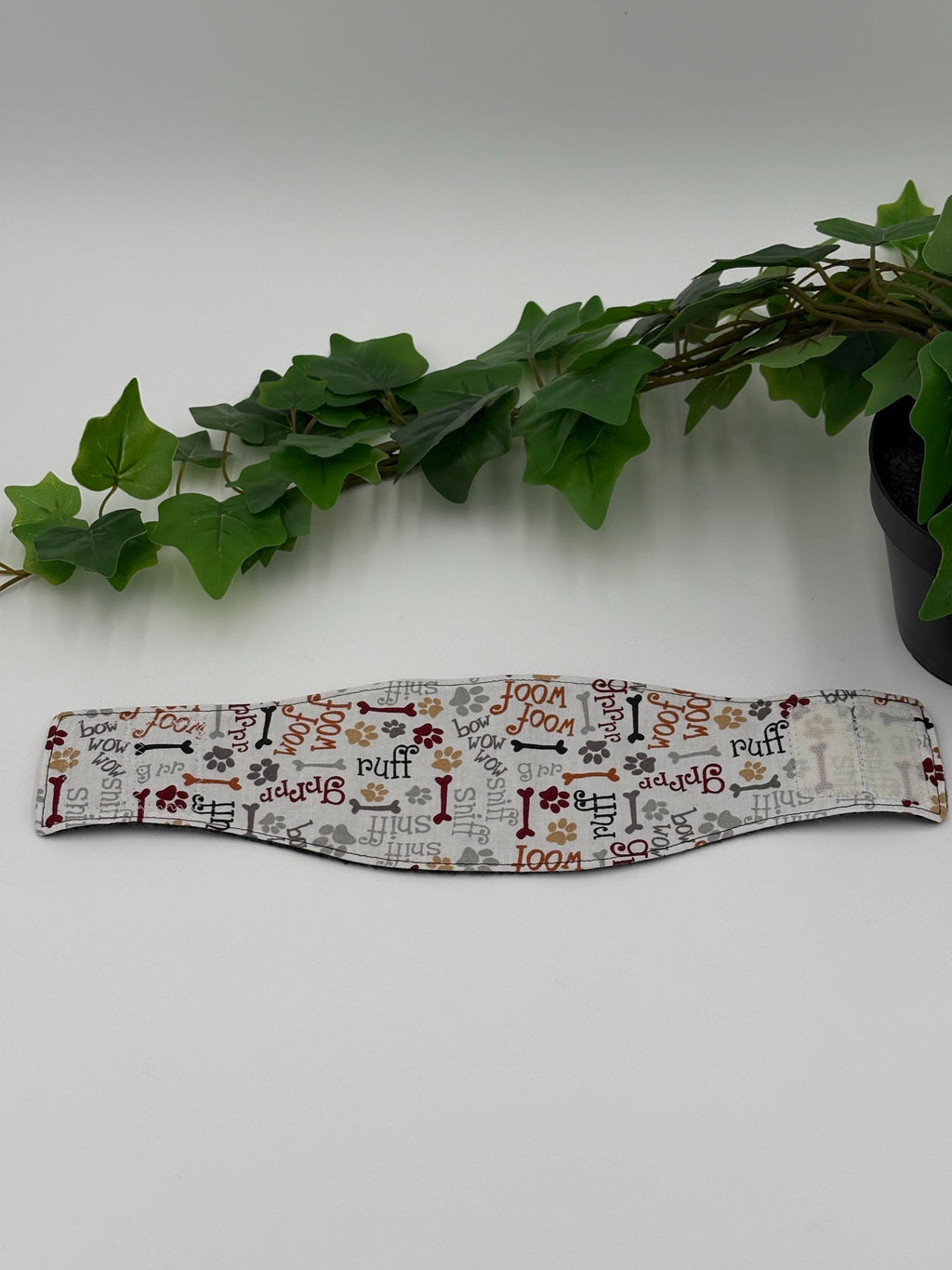 patterned belly band laid out flat on a white background next to green plant