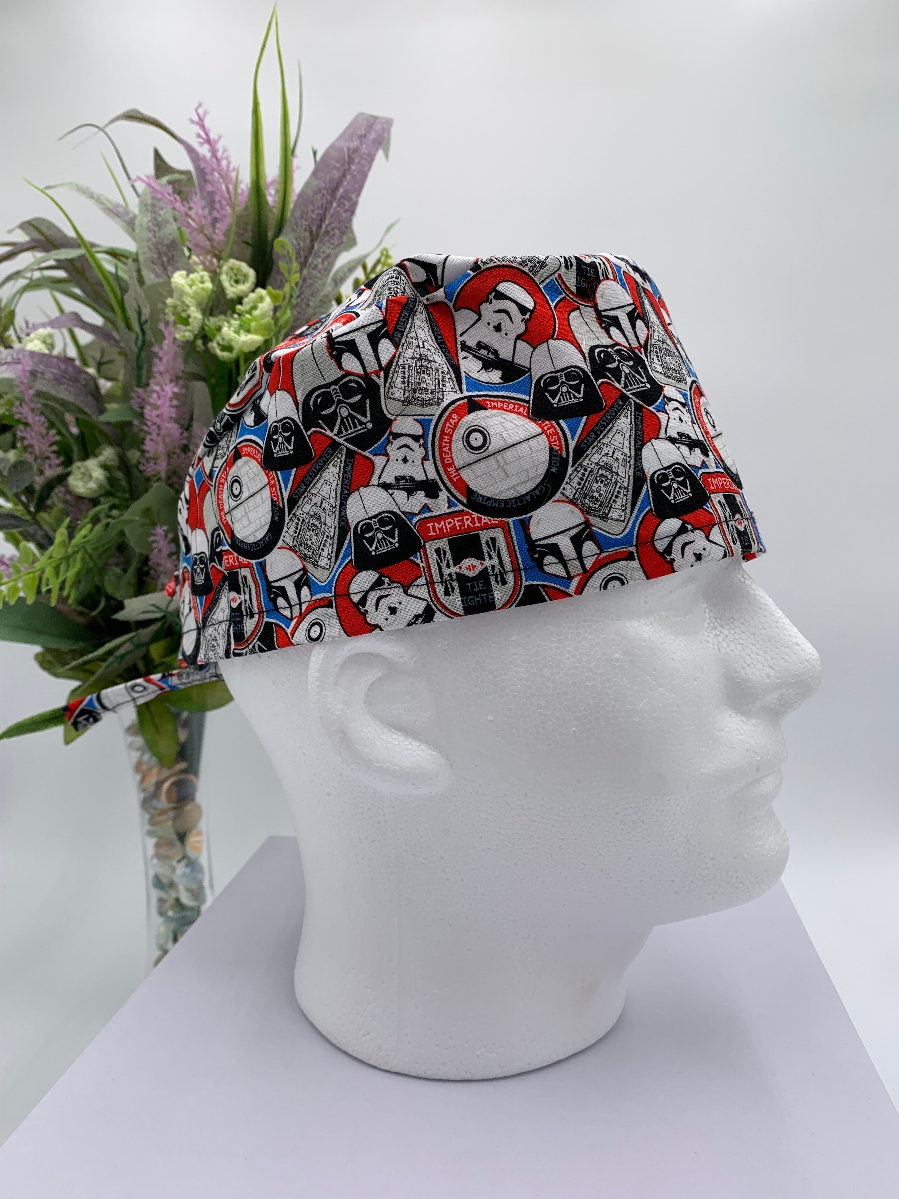 Colorful Star Wars scrub cap on a mannequin head with flowers, against a white background