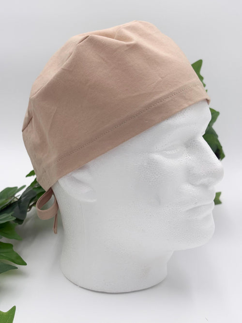 Beige scrub cap on a mannequin head with a white background