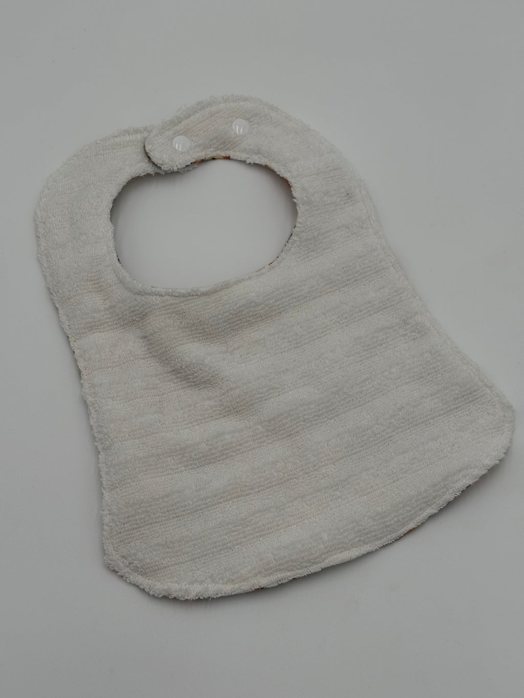 White terry cloth baby bib on a gray background