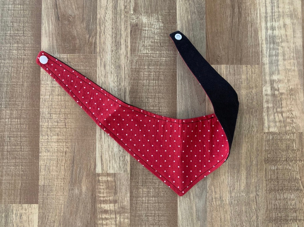 Red with white polka dot pet bandana showing the inside with black fabric on a wooden floor