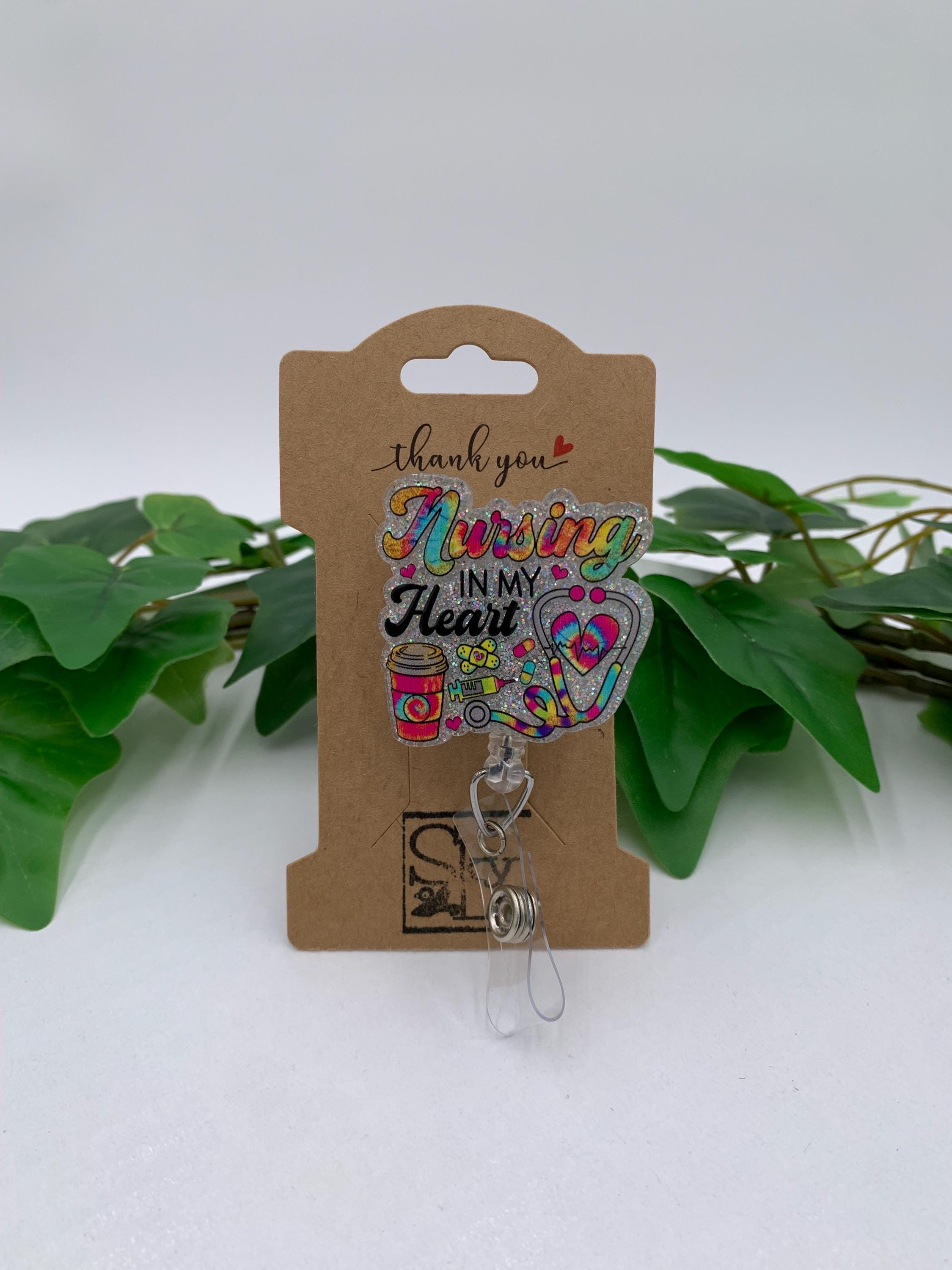 Retractable badge holder with colorful design on a brown card, surrounded by green leaves.