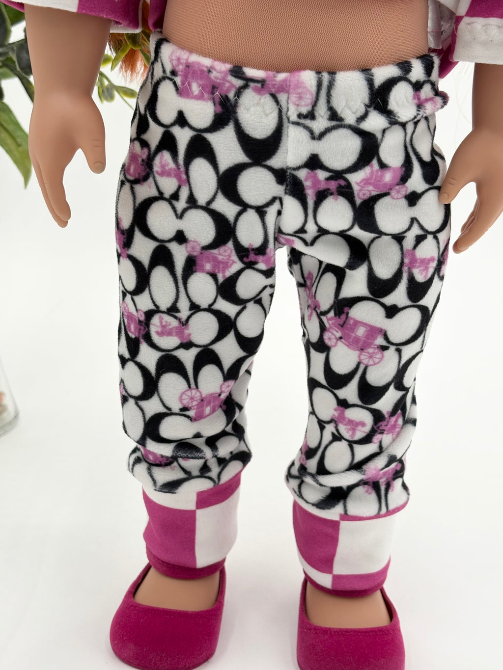 Doll wearing a black and white pajama pants outfit with pink accents