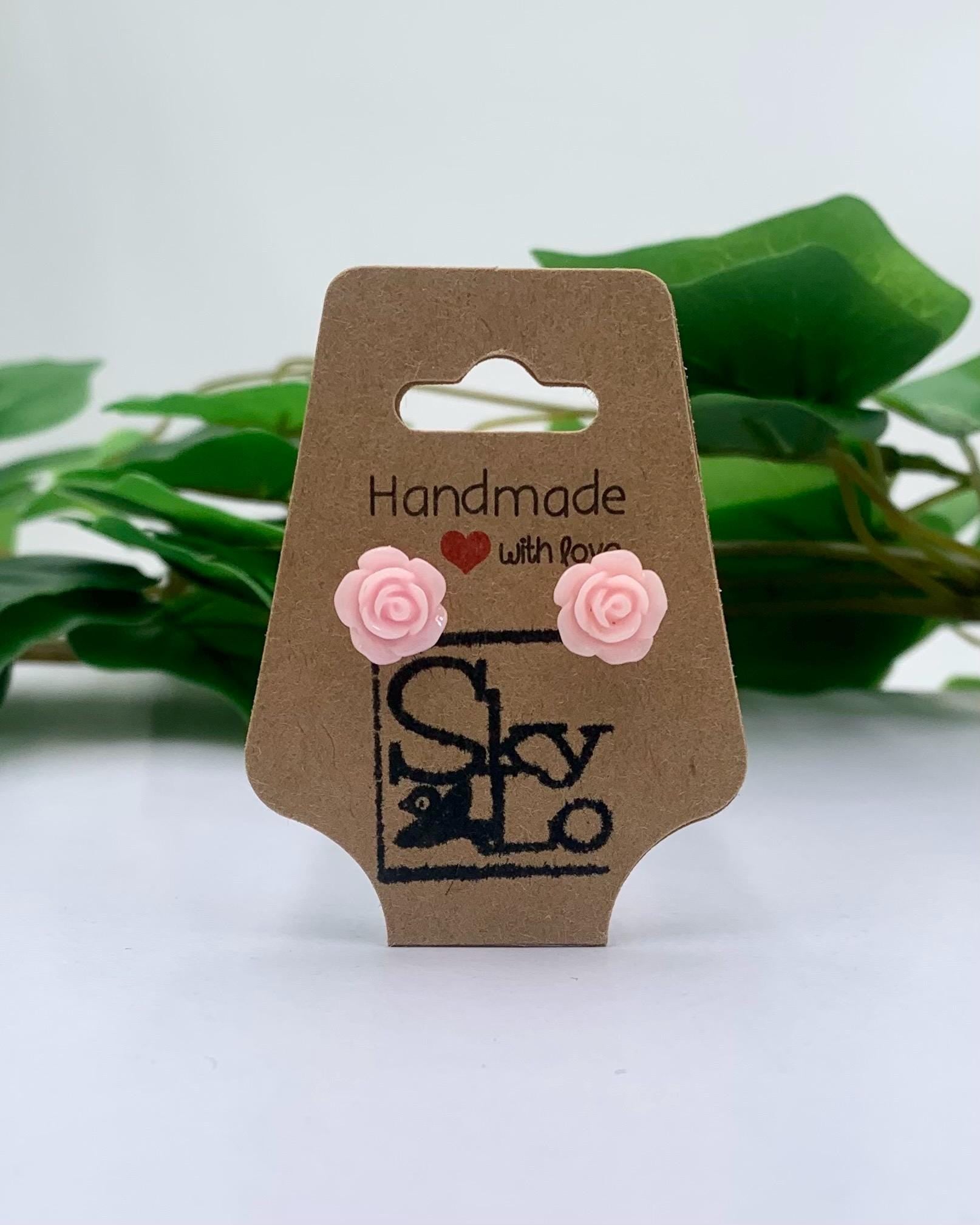 Baby Pink rose-shaped earrings on a 'Handmade with Love' branded card with green leaves in the background.