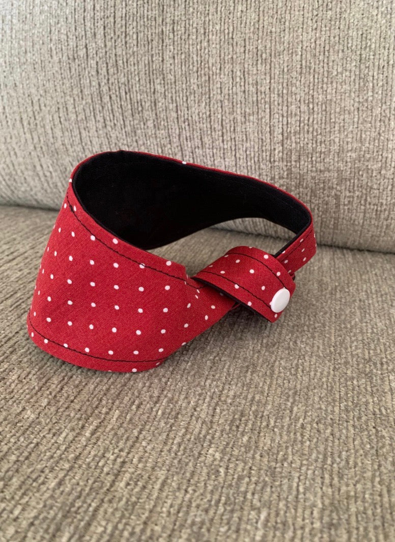 The back of a tied Red with white polka dot pet bandana on a beige couch