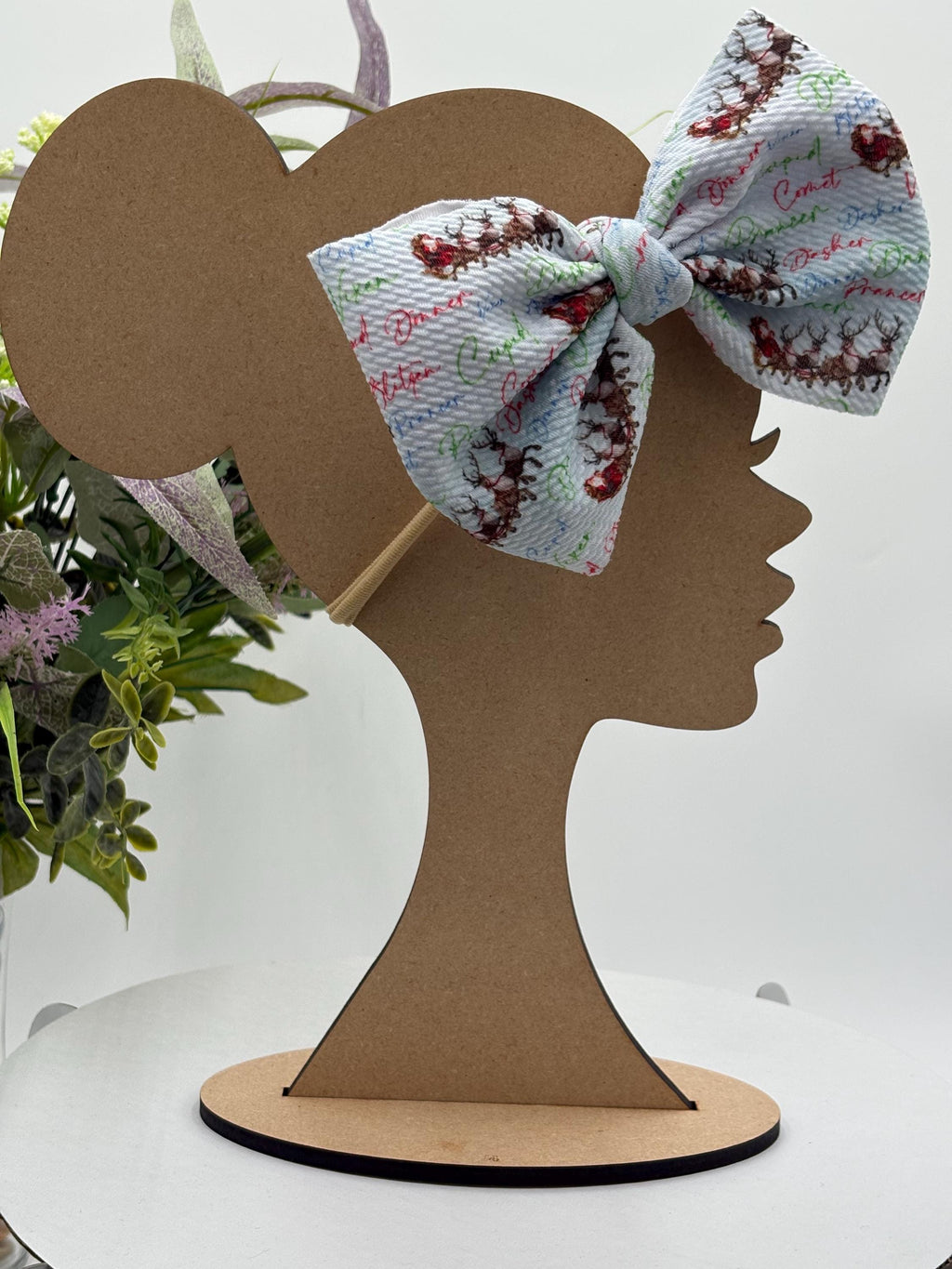 Nylon Headband with a decorative christmas themed big bow on a mannequin head silhouette against a white background