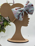 Nylon Headband with a decorative christmas themed big bow on a mannequin head silhouette against a white background