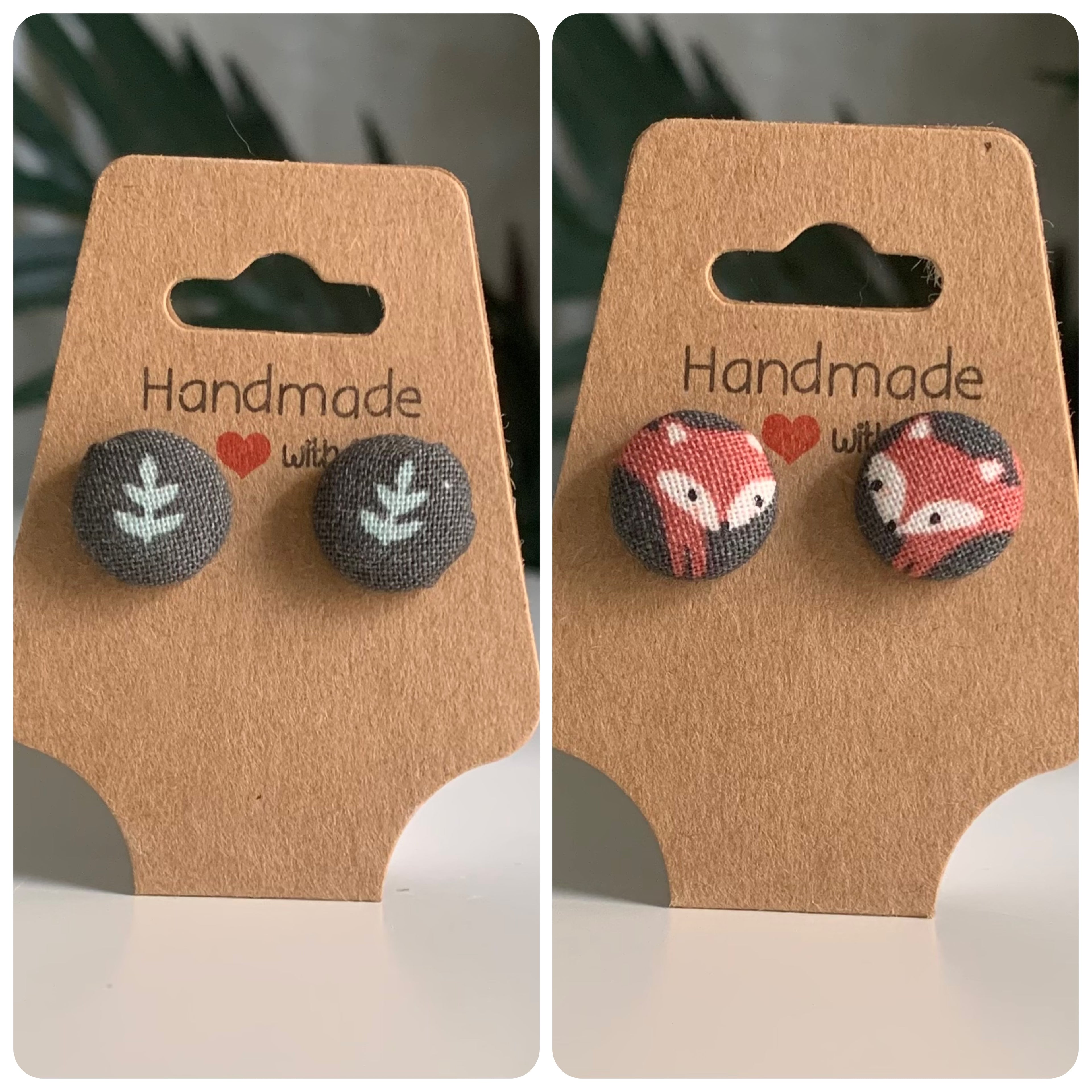 Two pairs of handmade earrings, a green background with a leaf in it and a green background with a fox on it, on brown card backs with 'Handmade with Love' text.