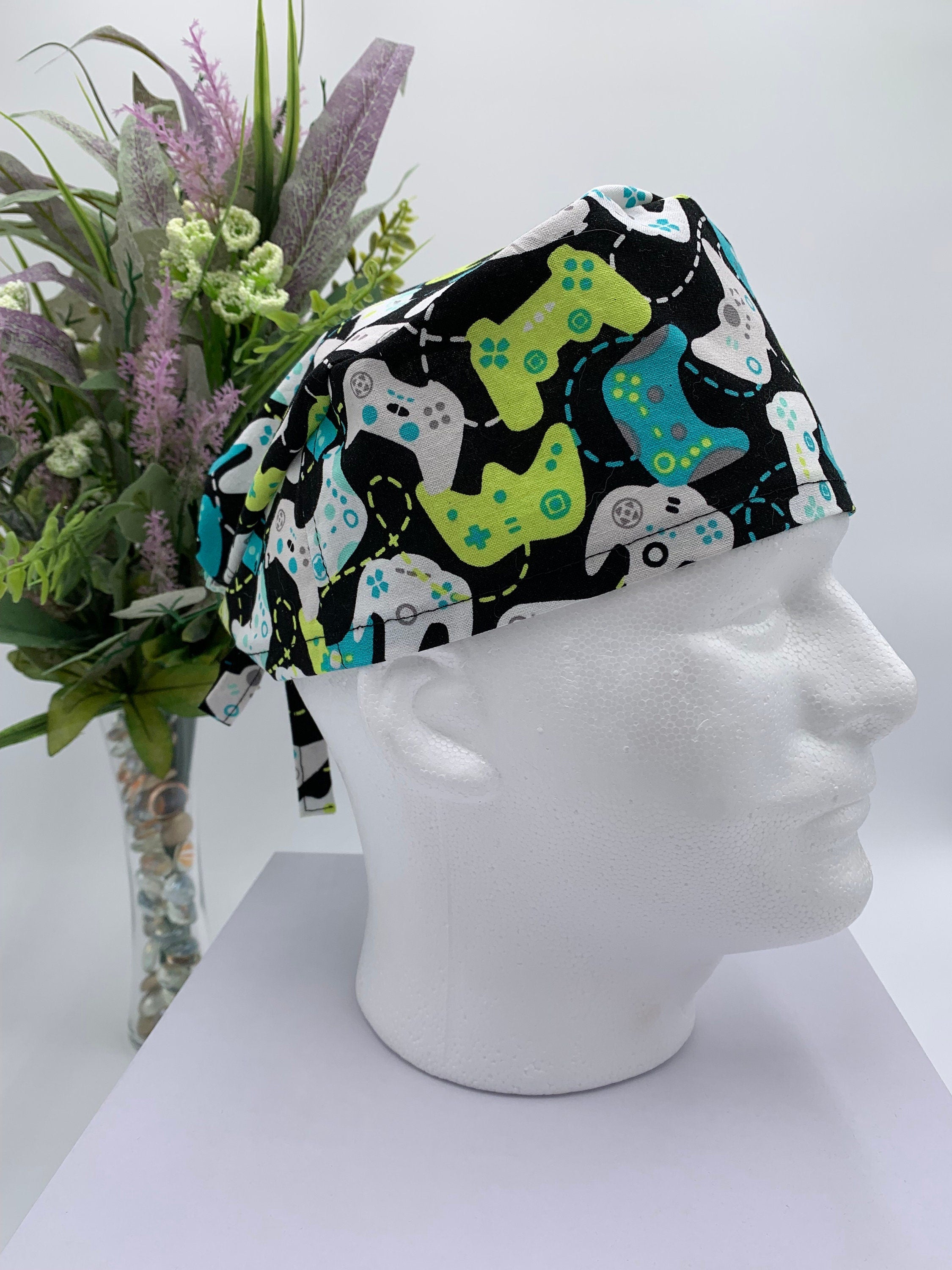 Colorful game controller scrub cap on a mannequin head with a bouquet of flowers in the background