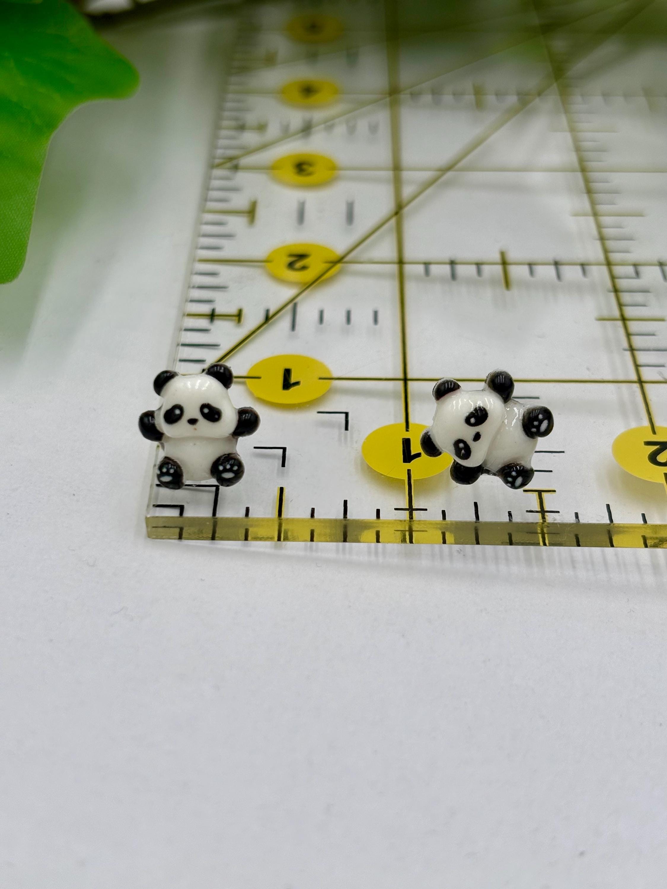 Two panda-shaped earrings on a ruler for scale