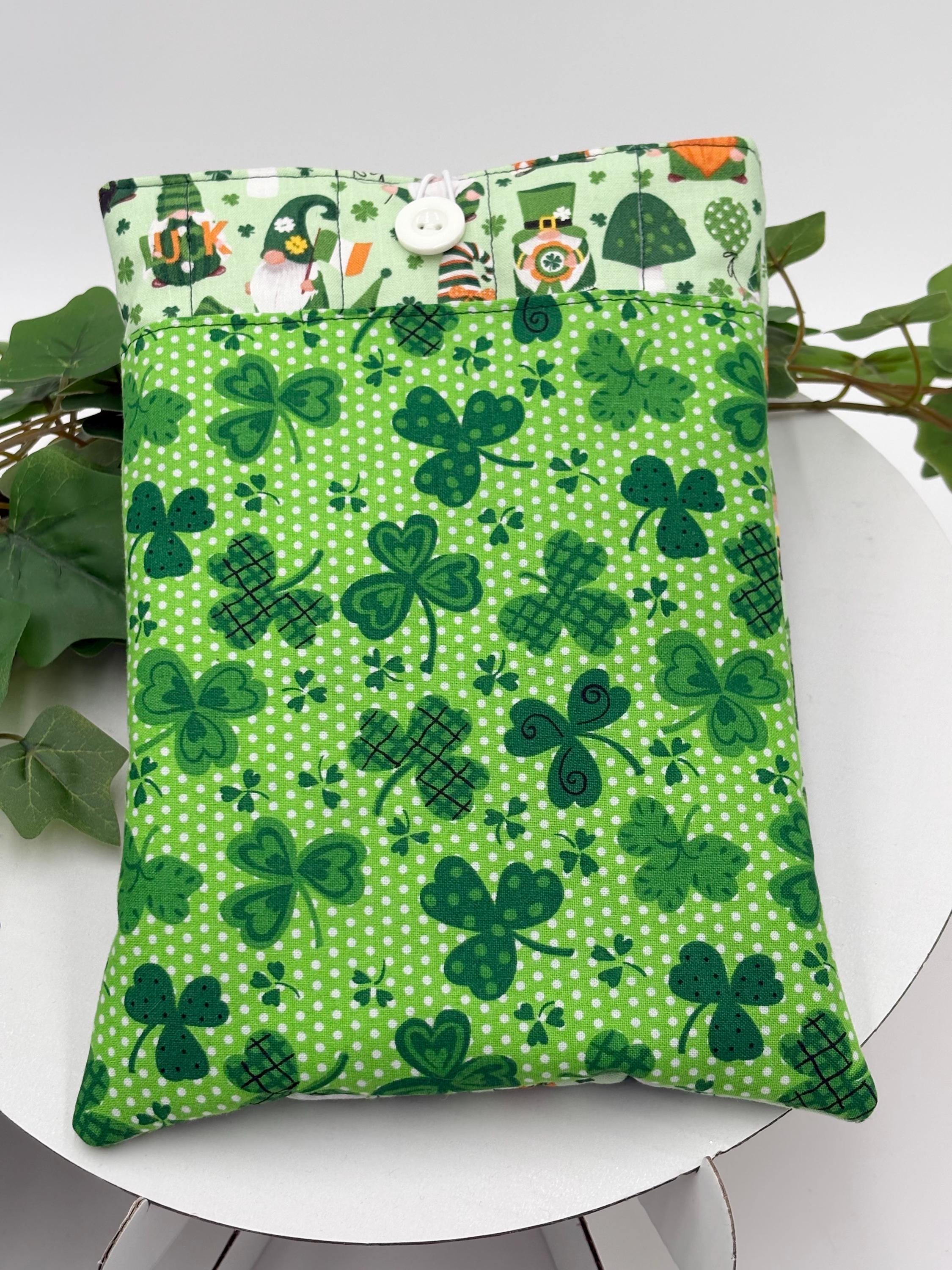 Green saint Patrick’s day gnomes and shamrocks patterned book sleeve on a white surface with green plants