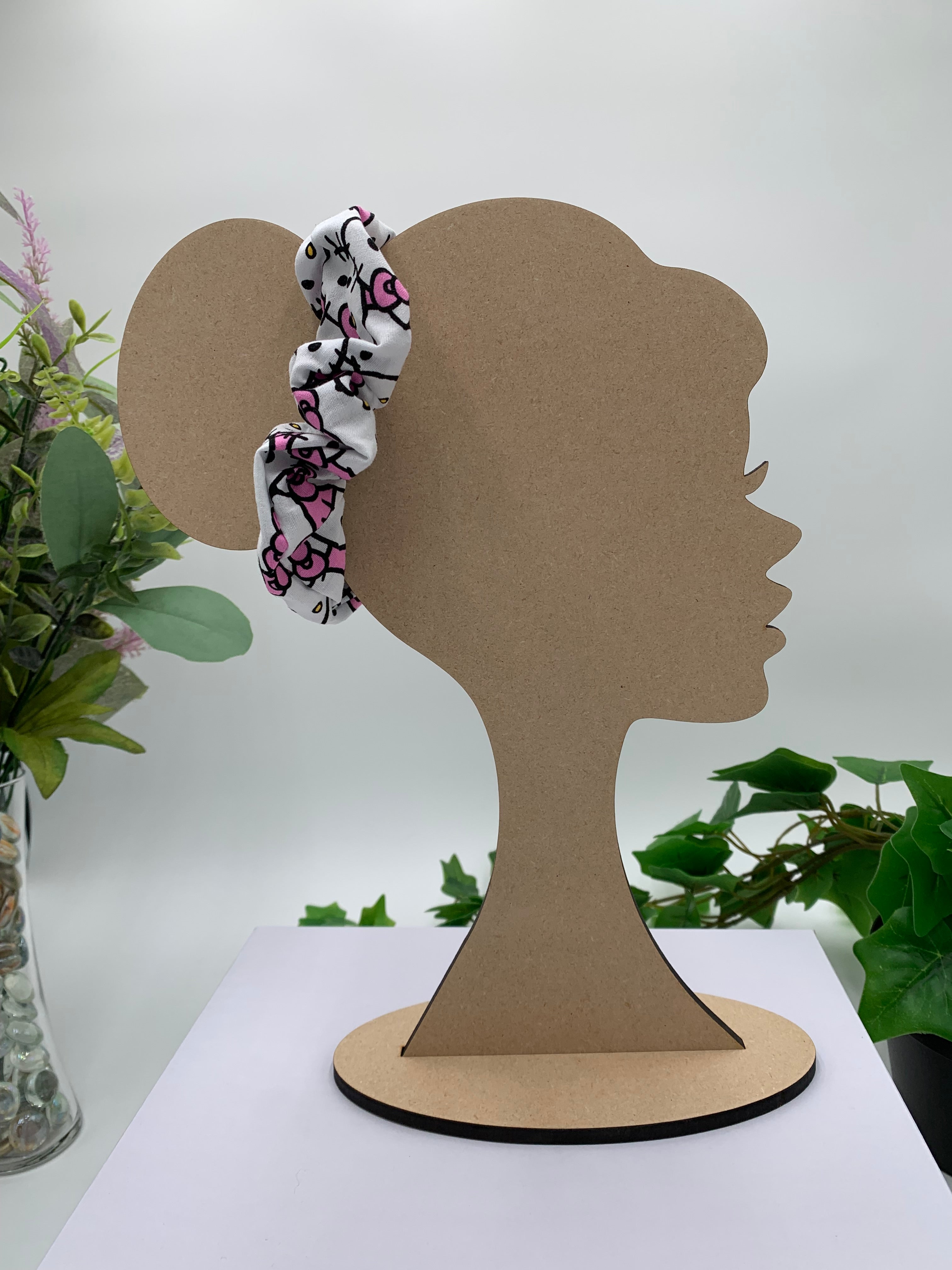 Mannequin Silhouette head with a cat themed scrunchie on a white background with greenery