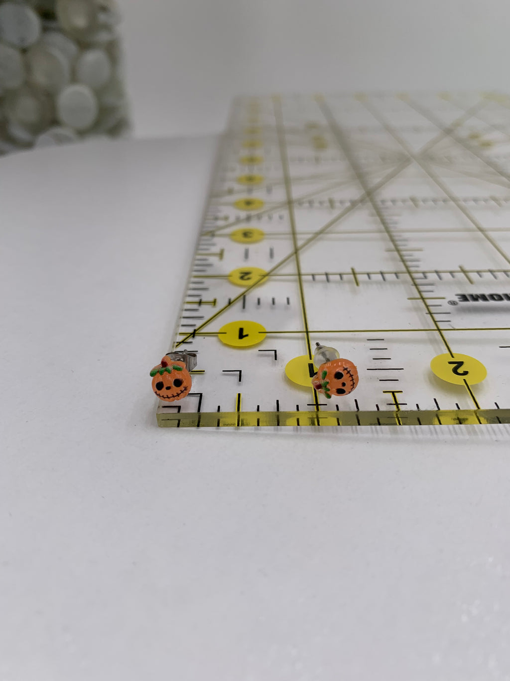 Close-up of a ruler with jack-o-lantern earrings on a white background