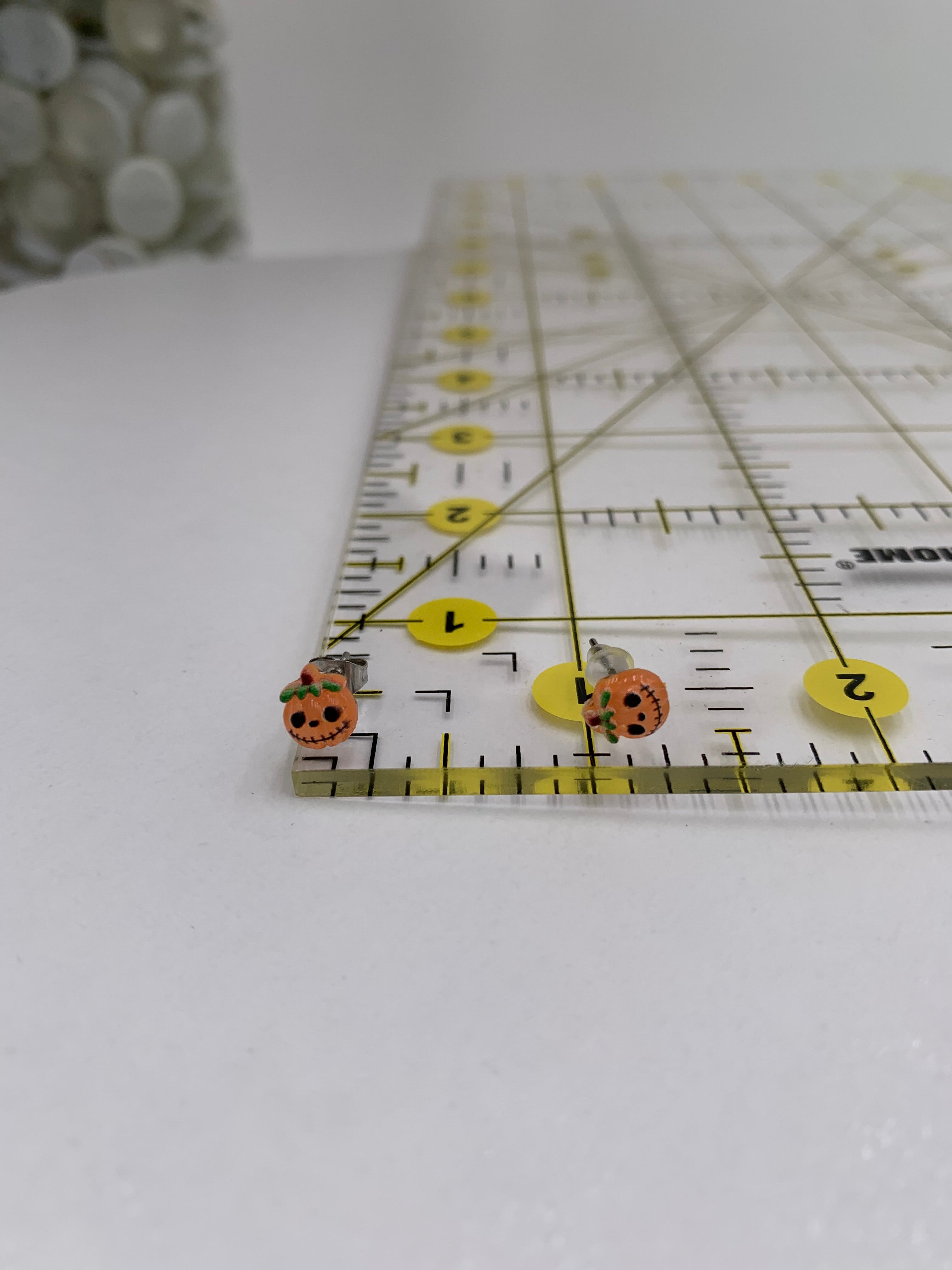 Close-up of a ruler with jack-o-lantern earrings on a white background