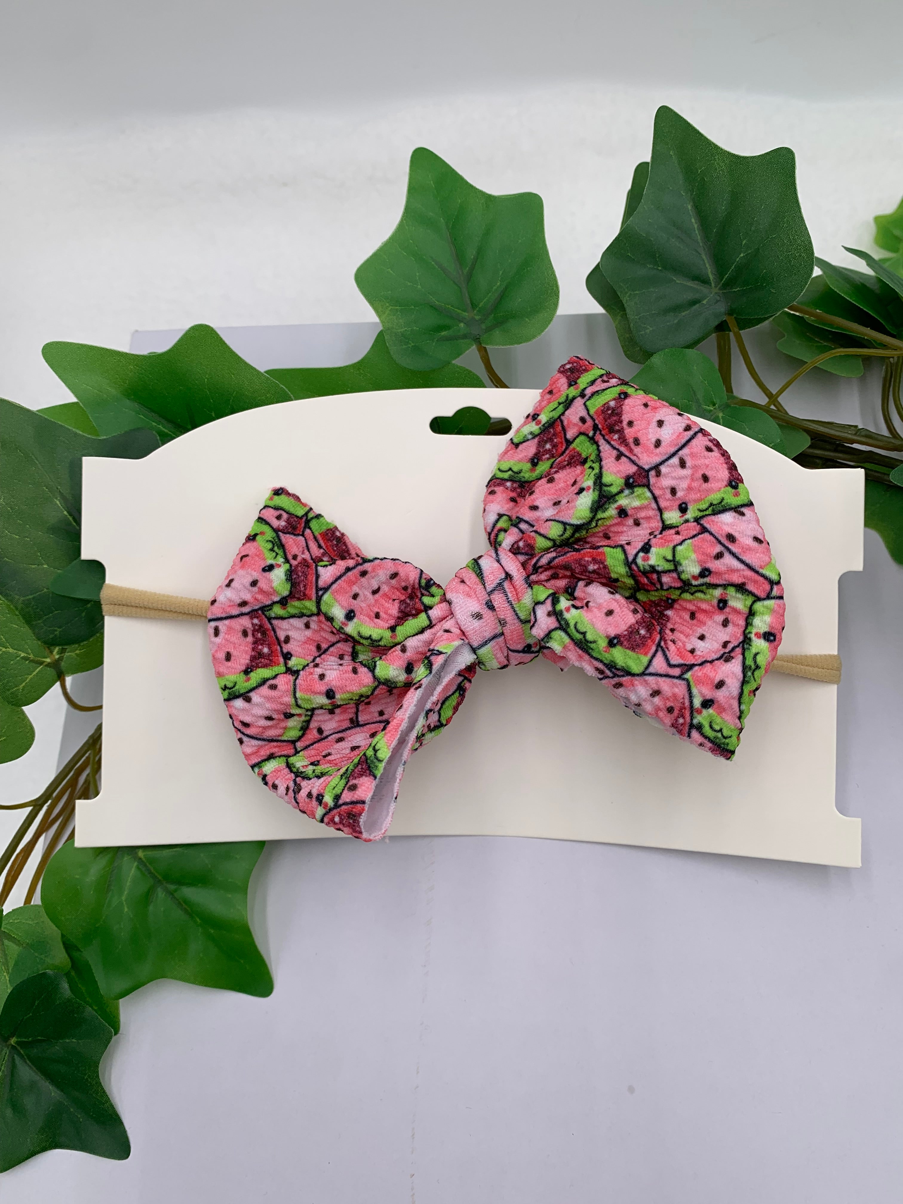 watermelon patterned big bow nylon headband on a white card with leaves in the background