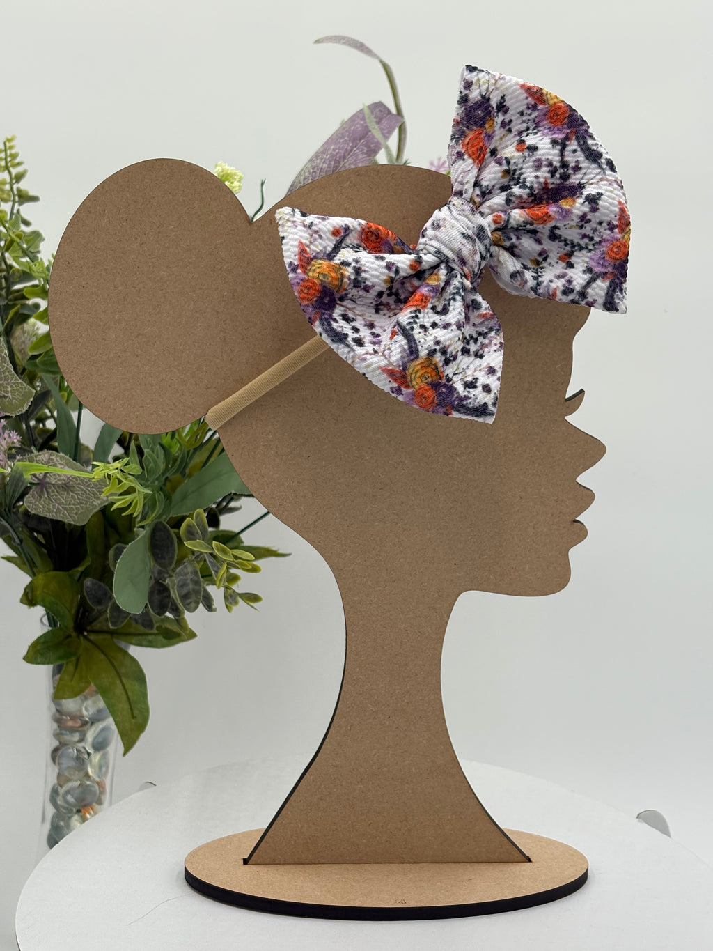 Autumn floral themed big bow nylon headband on a mannequin head with a white background and greenery 