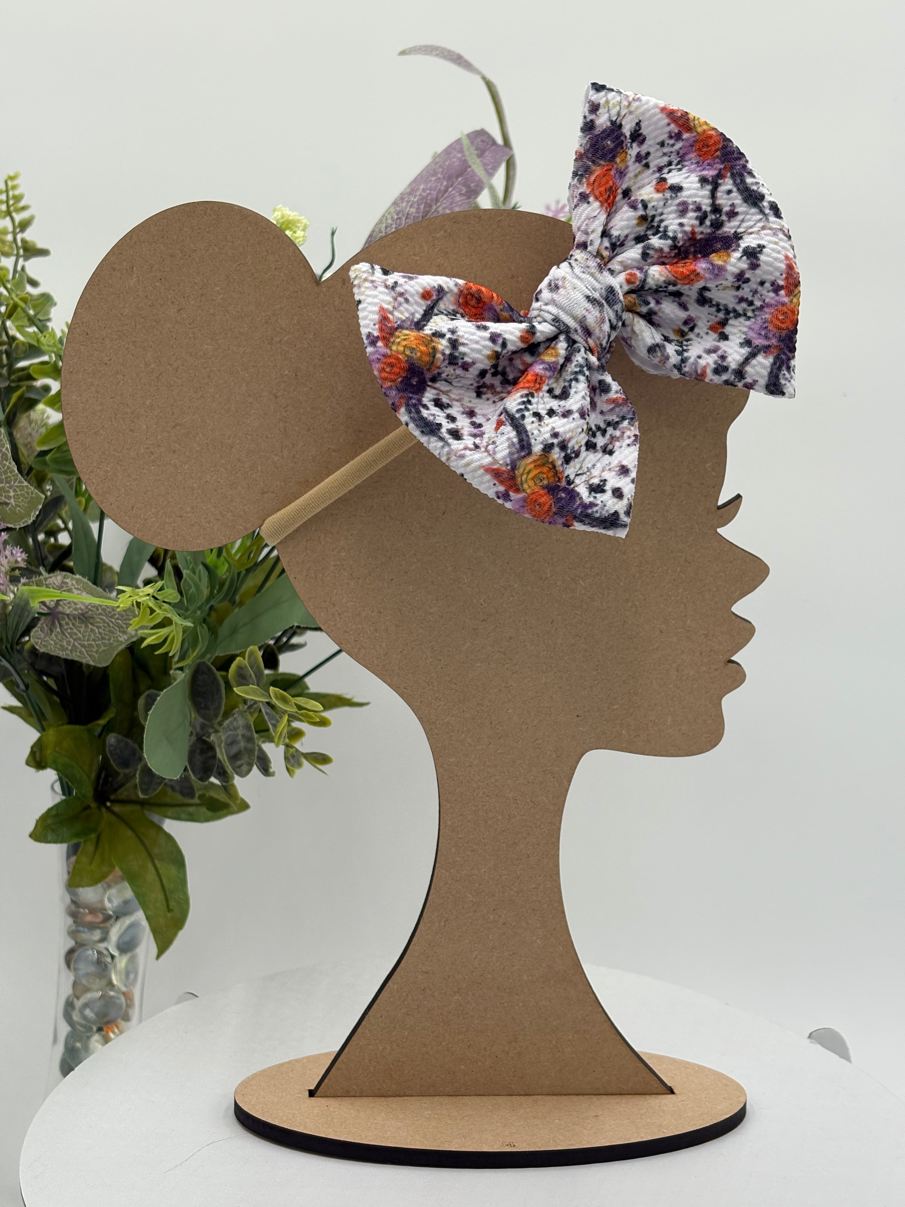 Autumn floral themed big bow nylon headband on a mannequin head with a white background and greenery 