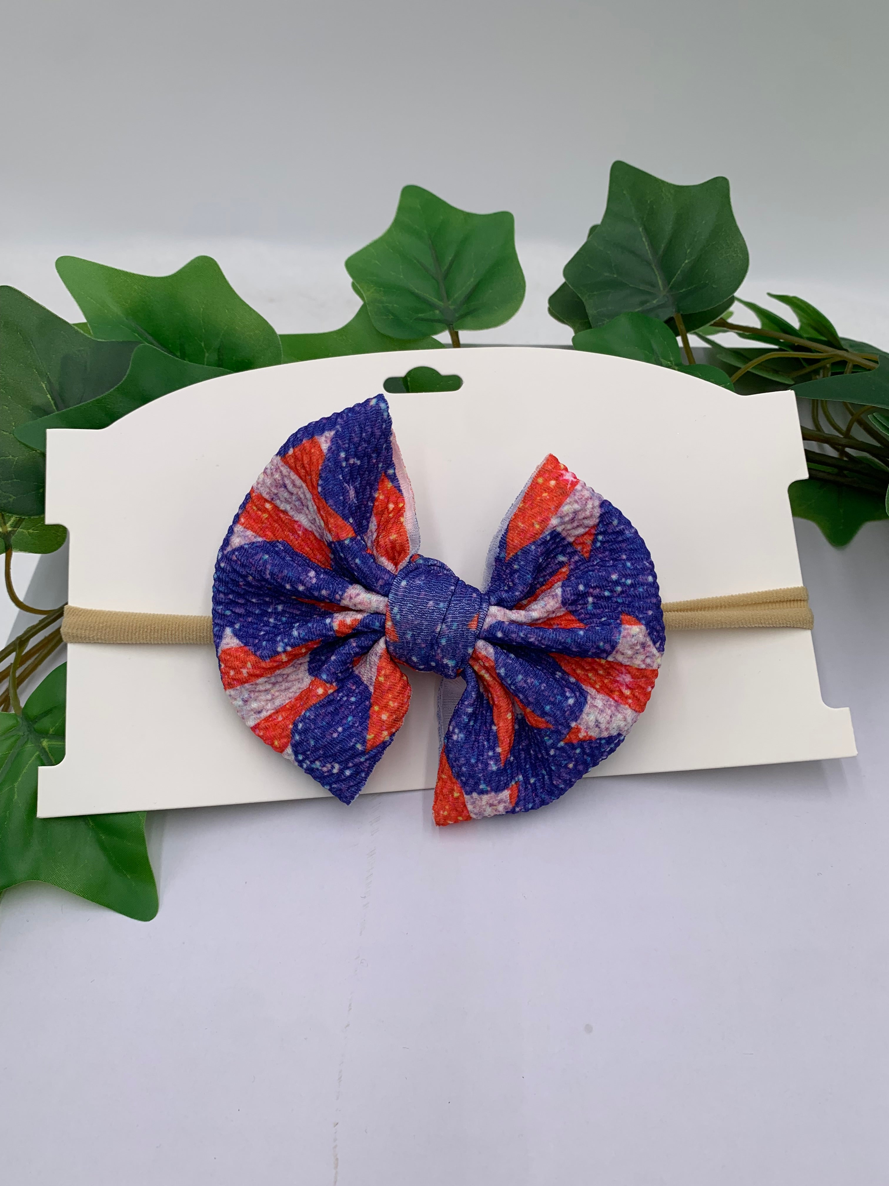 4th of july color star patterned big bow nylon headband on a white card with leaves in the background