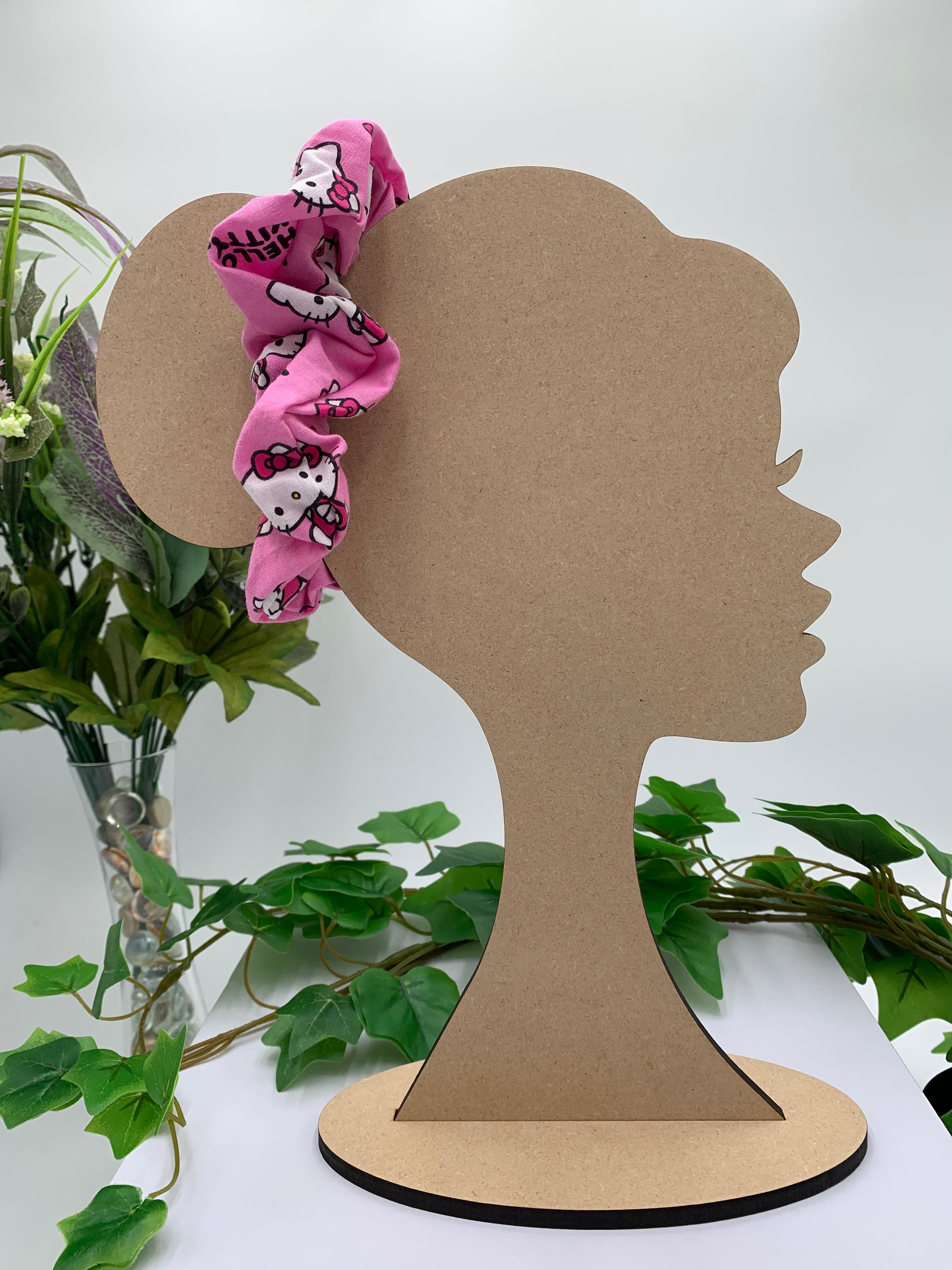Mannequin Silhouette head with a cat themed scrunchie on a white background with greenery