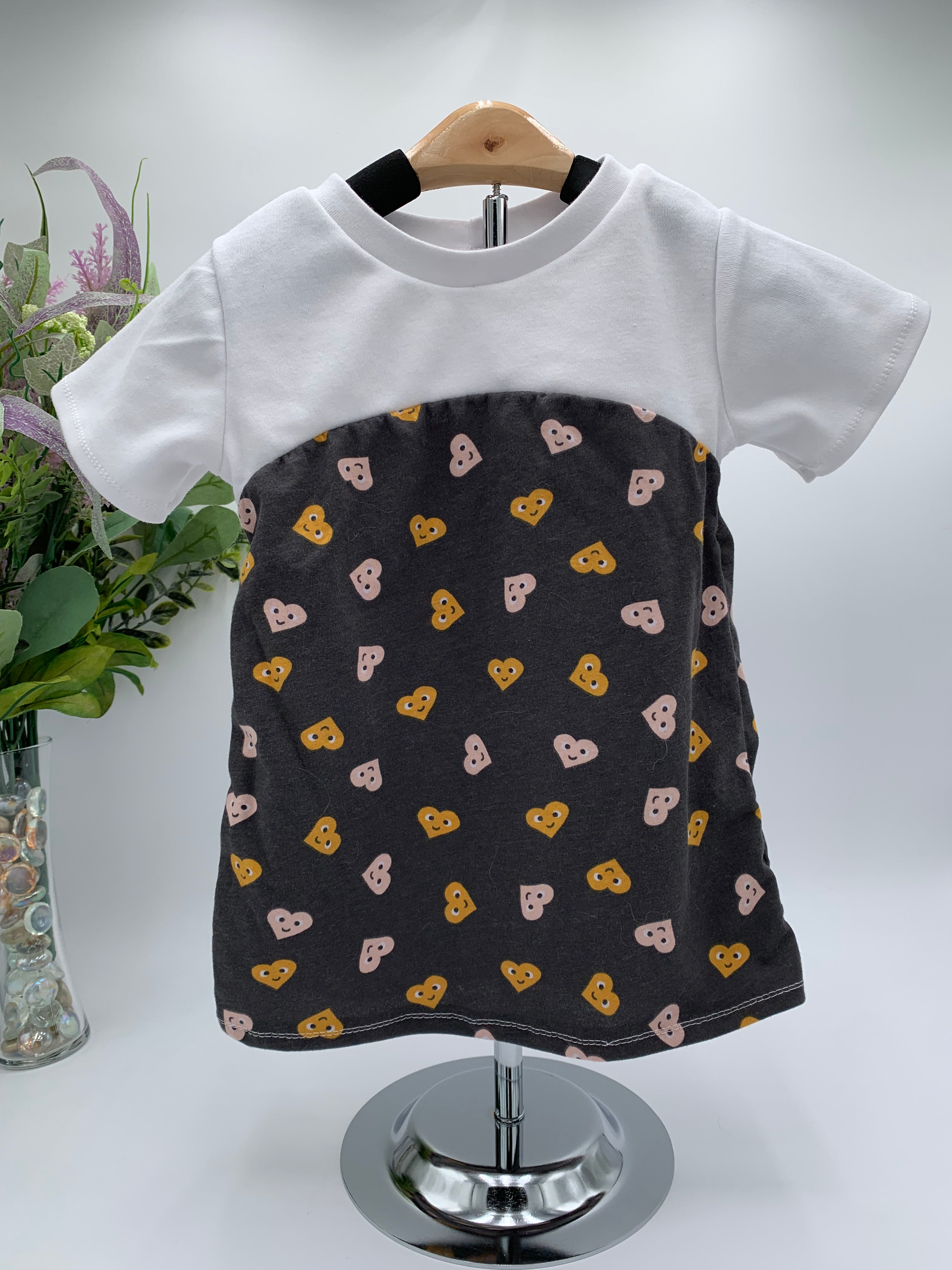 Toddler shirt with white top a d ray bottom with hearts on a white background with a vase of flowers in the background 