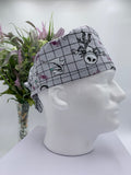 Mannequin head wearing a nightmare before christmas scrub cap with a decorative plant in the background.