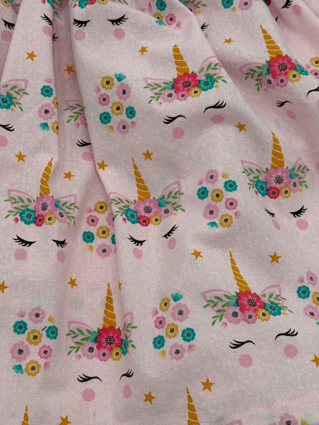 Fabric with unicorn and floral pattern on a pink background