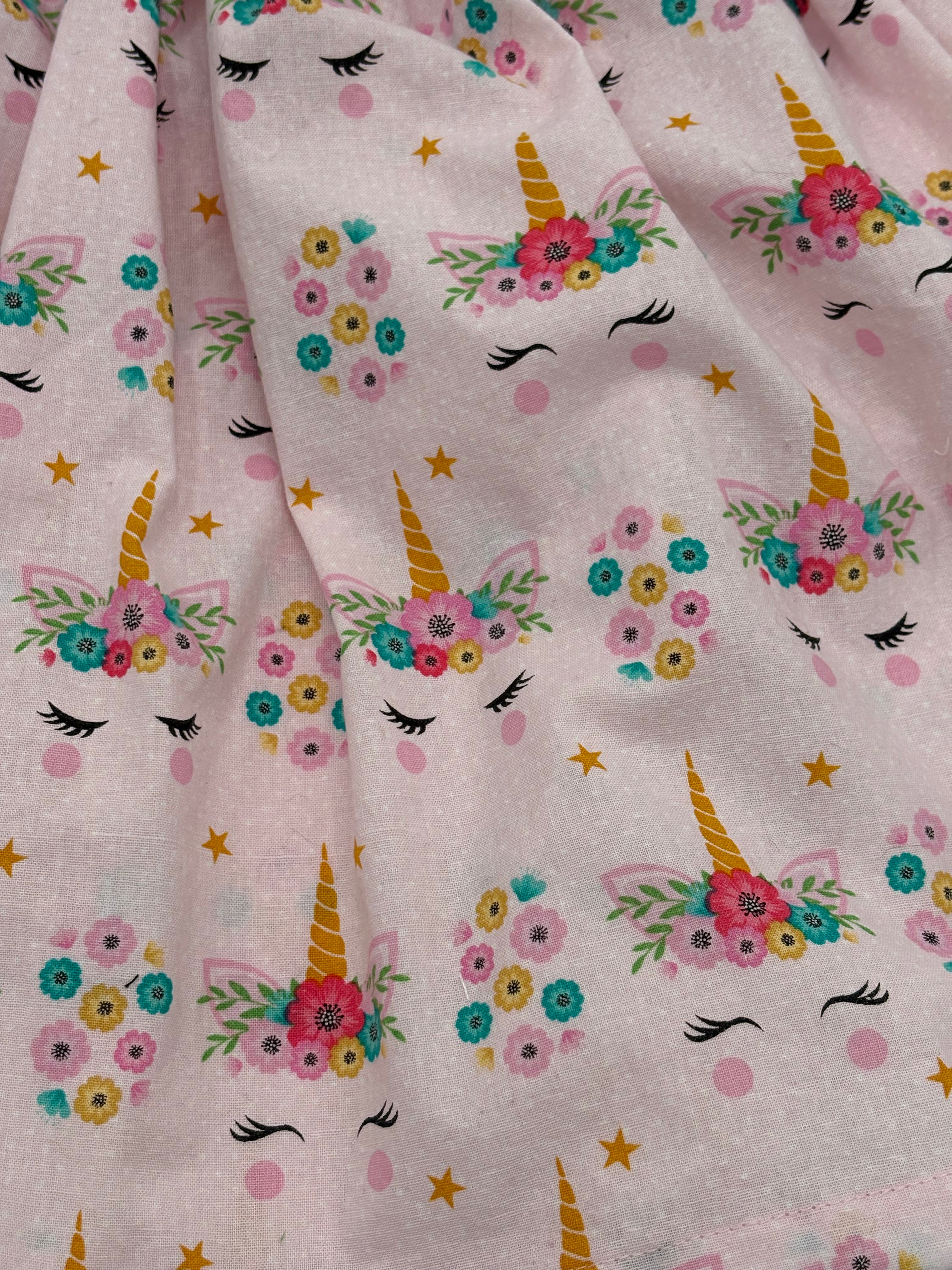 Fabric with unicorn and floral pattern on a pink background