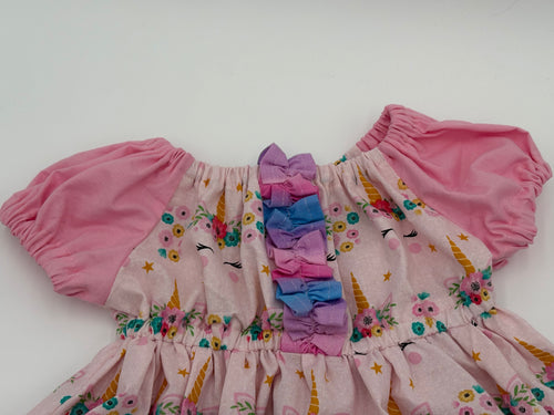 Children's outfit with pink floral dress with unicorn designs on a white background
