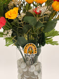 Bouquet of flowers with a rainbow sunflower with text "Teacher" badge holder in a clear vase on a white background