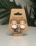Faerie shaped earrings with a Kraft branded label on a neutral background with a green plant. 
