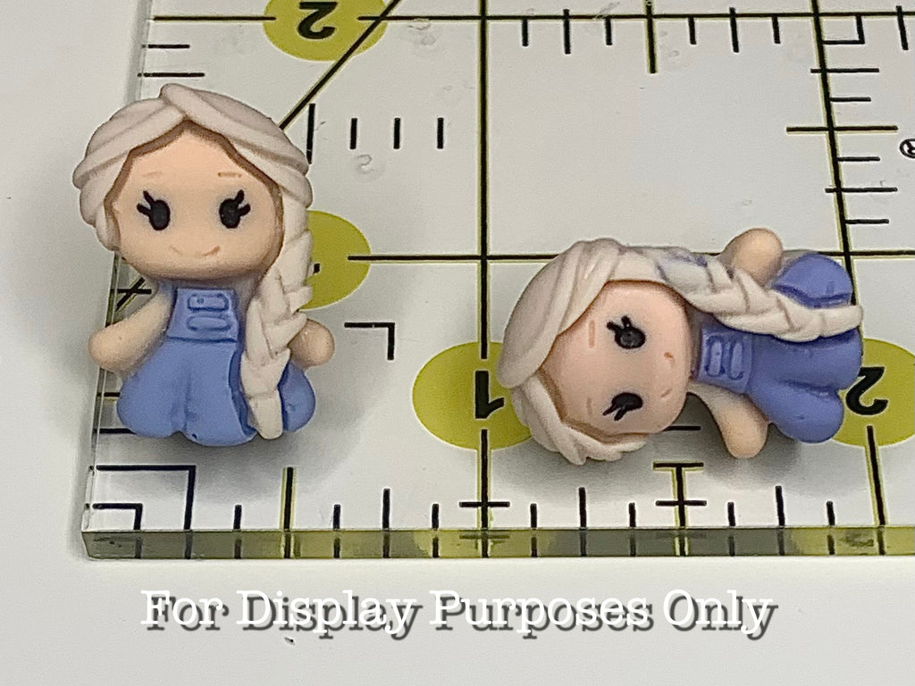 Princess shaped earring next to a ruler with measurement markings at 1 inch and 1/2 inch