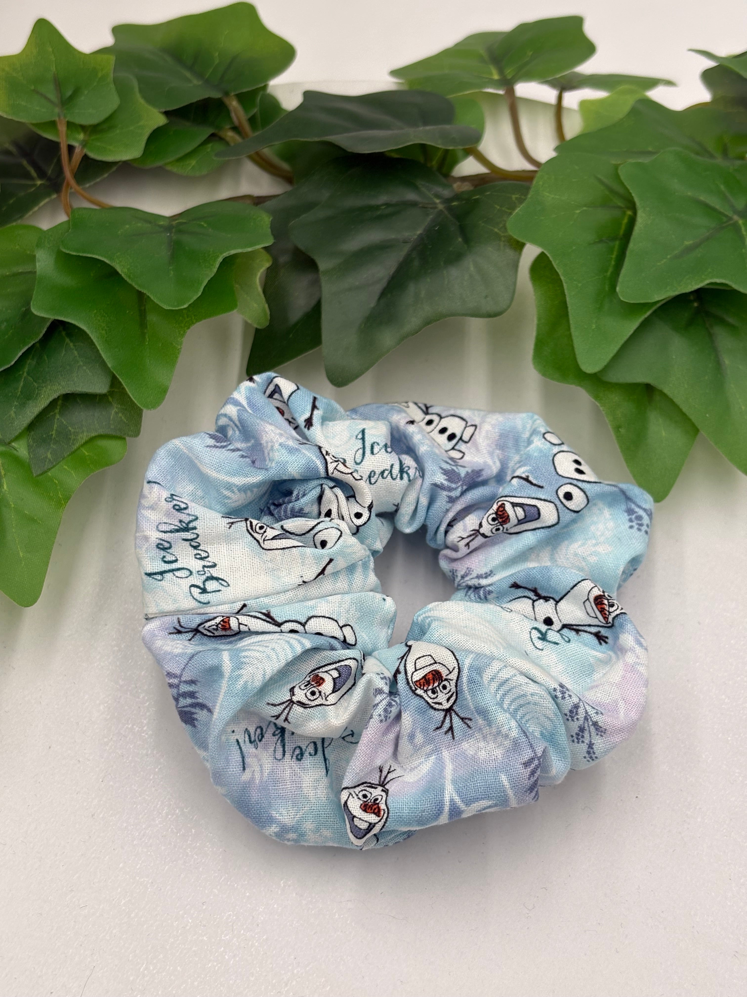 Scrunchie with cartoon character design on a white background with green leaves.