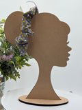 Gray with multicolored polka dots themed scrunchie on a mannequin head with a white background and greenery 