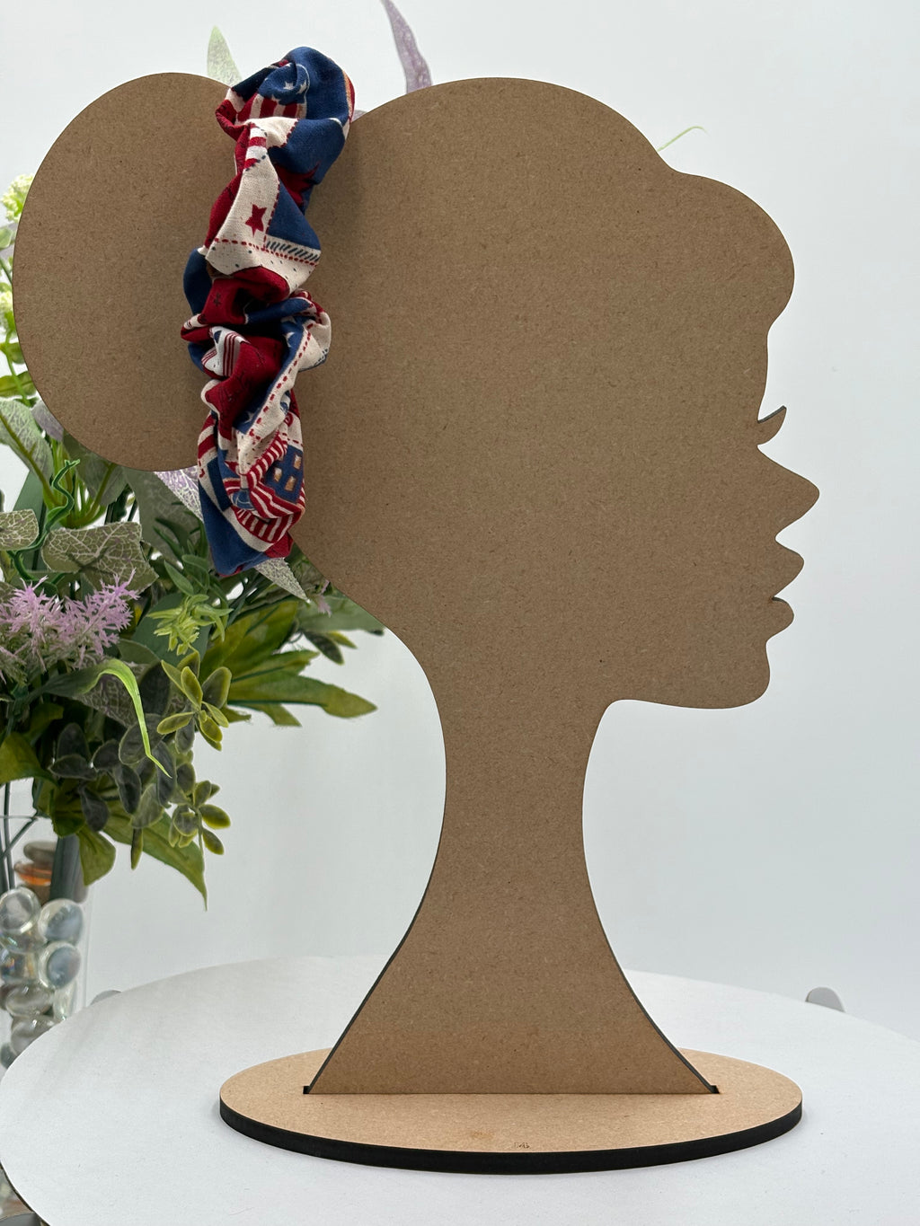 4th of July themed scrunchie on a mannequin head with a white background and greenery 