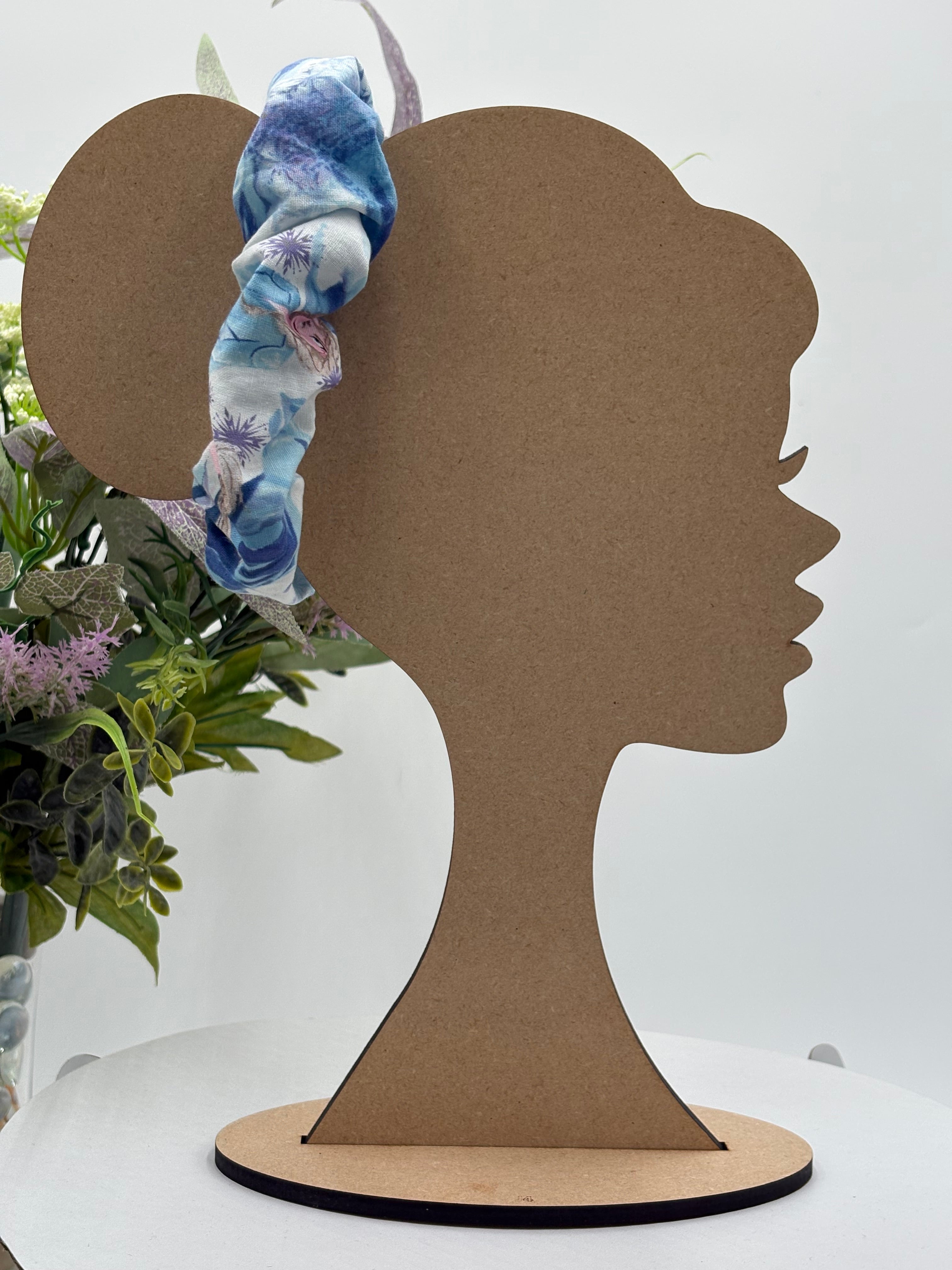 multicolor cartoon character themed scrunchie on a mannequin head with a white background and greenery 