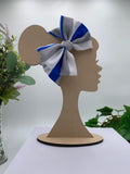 Wooden mannequin head cutout with a blue, white, and gray bow, against a white background with greenery.