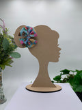 Colorful hair bow on a wooden silhouette of a girl against a white background with plants.