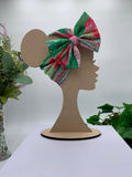 Watermelon colors themed big bow headband on a mannequin head with a white background and greenery 