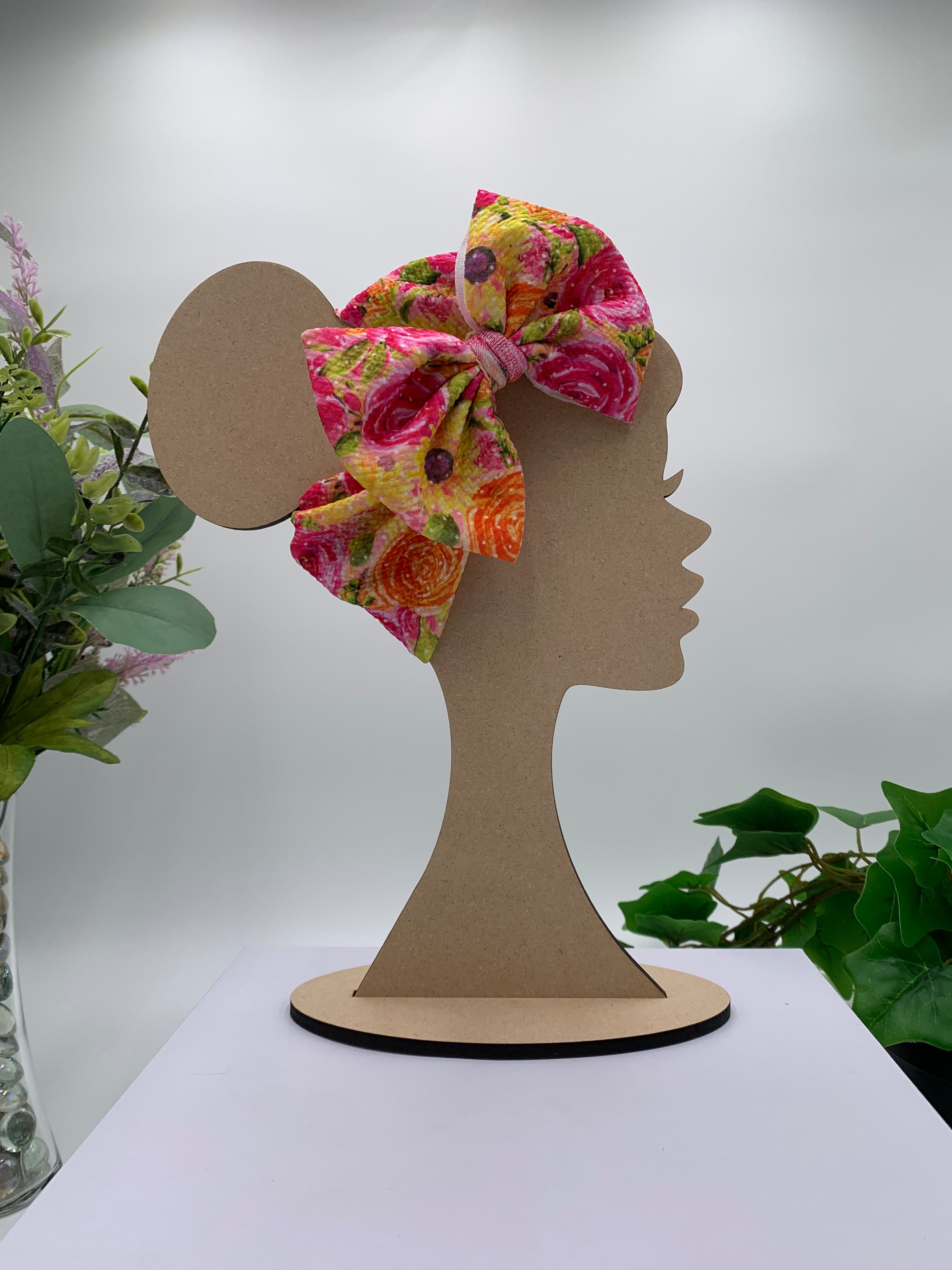 Spring flowers themed big bow headband on a mannequin head with a white background and greenery 